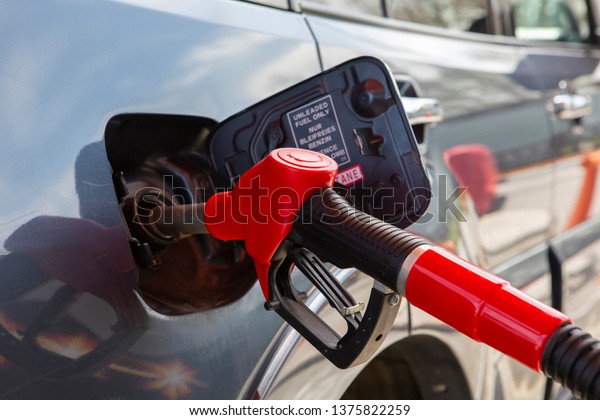 Fill the car with fuel. The car is filled with\
gasoline at a gas station. Gas station pump. Man refueling gasoline\
with fuel in a car, holding a nozzle. Limited depth of field.\
Blurred image Close-up.