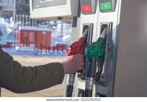 To fill\
up the car with gasoline at the gas station, a man pours gasoline\
into the tank of a white car in\
winter.