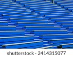 Fill the frame with the pattern from the old painted blue grandstand, a landscape image of wooden grandstand. No people in the image.