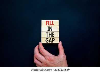 Fill in the gap symbol. Concept words Fill in the gap on wooden blocks on a beautiful black table black background. Businessman hand. Business, motivational and fill in the gap concept.