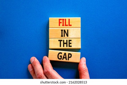 Fill in the gap symbol. Concept words Fill in the gap on wooden blocks on a beautiful blue table blue background. Businessman hand. Business, motivational and fill in the gap concept.
