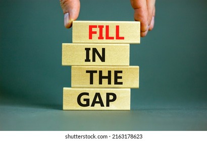 Fill in the gap symbol. Concept words Fill in the gap on wooden blocks on a beautiful grey table grey background. Businessman hand. Business, motivational and fill in the gap concept.