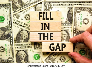 Fill in the gap symbol. Concept words Fill in the gap on wooden blocks on a beautiful background from dollar bills. Businessman hand. Business, motivational and fill in the gap concept.