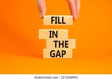 Fill in the gap symbol. Concept words Fill in the gap on wooden blocks on a beautiful orange table orange background. Businessman hand. Business, motivational and fill in the gap concept.