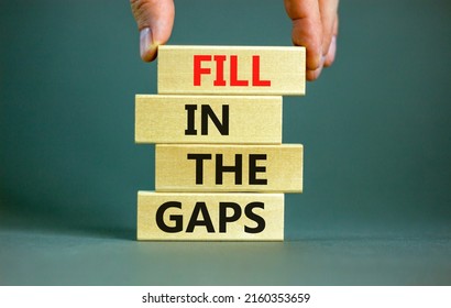 Fill in the gaps symbol. Concept words Fill in the gaps on wooden blocks on a beautiful grey table grey background. Businessman hand. Business, motivational and fill in the gaps concept.