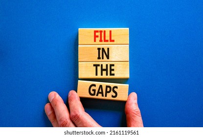 Fill in the gaps symbol. Concept words Fill in the gaps on wooden blocks on a beautiful blue table blue background. Businessman hand. Business, motivational and fill in the gaps concept.