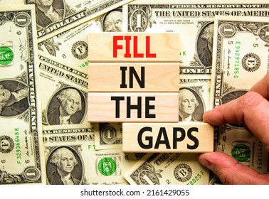 Fill in the gaps symbol. Concept words Fill in the gaps on wooden blocks on a beautiful background from dollar bills. Businessman hand. Business, motivational and fill in the gaps concept.