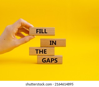 Fill in the gaps symbol. Concept words fill in the gaps on wooden blocks. Beautiful yellow background. Businessman hand. Business and fill in the gaps concept. Copy space.