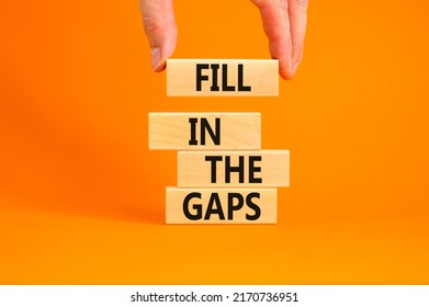 Fill in the gaps symbol. Concept words Fill in the gaps on wooden blocks on a beautiful orange table orange background. Businessman hand. Business, motivational and fill in the gaps concept.