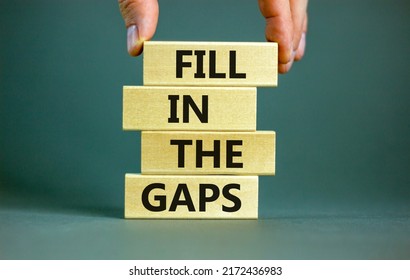 Fill in the gaps symbol. Concept words Fill in the gaps on wooden blocks on a beautiful grey table grey background. Businessman hand. Business, motivational and fill in the gaps concept.