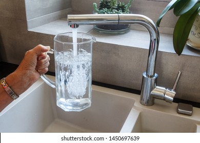 To Fill A Glass Jug With Tap Water At The Sink In A Kitchen