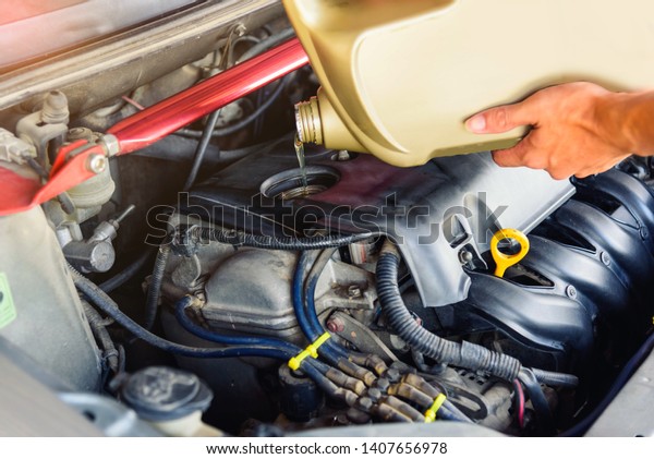 Fill the oil machine to engine of\
the car / worker take the Oil gallon to re-fill machine\
oil
