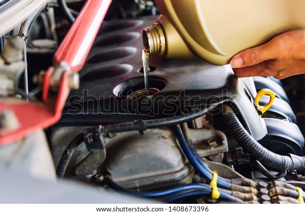 Fill the oil machine to engine of the\
car / worker take the Oil gallon to fill machine\
oil