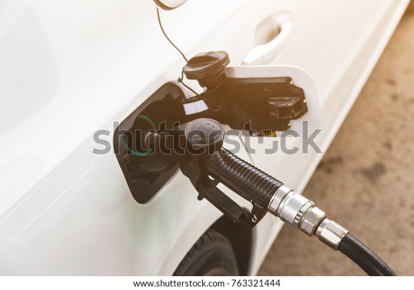 To fill the white car\
with fuel. Car fill with gasoline at a gas station. Gas station\
pump. Close up