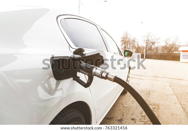 To fill the white car\
with fuel. Car fill with gasoline at a gas station. Gas station\
pump. Close up