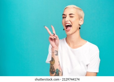 Fill the world with happiness. Studio shot of a confident young woman making a peace gesture against a turquoise background. - Shutterstock ID 2129744174