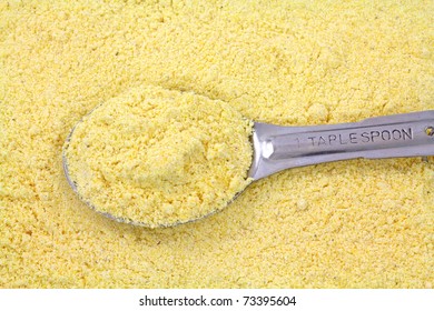 A Filled Tablespoon Atop A Layer Of Stone Ground Yellow Corn Meal.