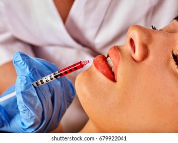 Filler injection for female forehead face. Plastic aesthetic facial surgery in beauty clinic. Silicone lips. Doctor in medical gloves with syringe injects lips augmentation. Preservation of youth.