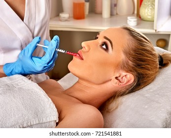 Filler injection for female lip face. Silicone lips in girl. Doctor in medical gloves with syringe injects lips augmentation.