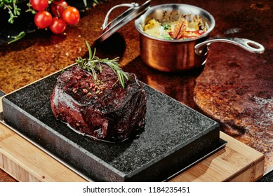 Fillet Of Mignon On A Black Plate On A Background Of Greens, Spices And Vegetables, On A Copper Sheet. Close Up