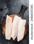 Fillets of codfish, raw cod fish meat. Black background. Top view.