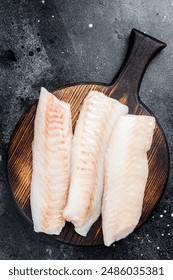 Fillets of codfish, raw cod fish meat. Black background. Top view.