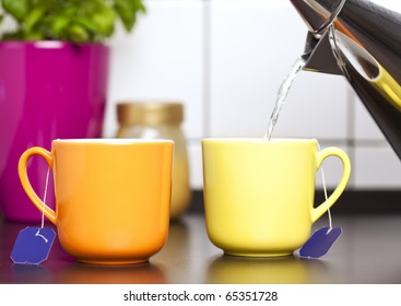 Filling Boiling Water From Kettle Into Two Cups With Teabags