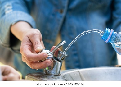 Filling a bottle with drinking water in a public drinking fountain. Thirst on a hot summer day. The man is thirsty. Pure mineral water. - Powered by Shutterstock