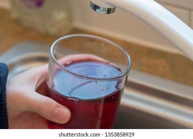 Filling Up A Drink Of Blackcurrant Cordial Juice With Water From A Running Kitchen Sink Tap