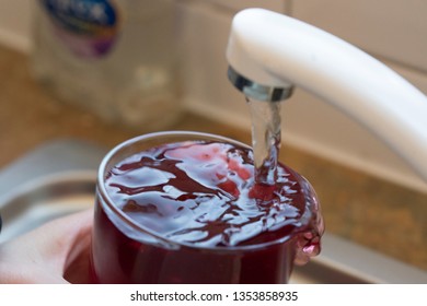 Filling Up A Drink Of Blackcurrant Cordial Juice With Water From A Running Kitchen Sink Tap