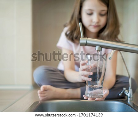 Filling glass with tap water. Modern faucet and sink in home kitchen. Child is pouring fresh drink to cup. Healthy lifestyle. Water quality check. World water monitoring day. Environmental concept