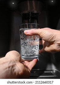 Filling glass with water dispenser of home fridge with two male hands point of view - Shutterstock ID 2112660317