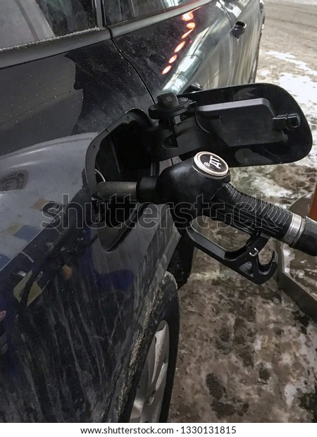The filling gun in\
a fuel tank of the car at gas station. The inscription in Russian\
\