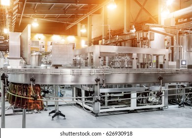 The filling machine pours beer into plastic PET bottles. Brewing production, abstract industrial background.