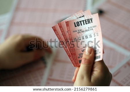 Filling out a lottery ticket. A young woman holds the lottery ticket with complete row of numbers on the lottery blank sheets background. Gambling concept