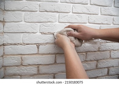 Filling The Seams In A Decorative White Stone In The Form Of A Brick On The Wall. Laying Decorative Stone On The Wall