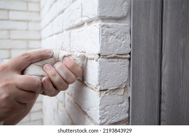 Filling The Seams In A Decorative White Stone In The Form Of A Brick On The Wall. Laying Decorative Stone On The Wall