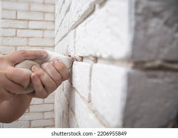 Filling The Seams In A Decorative White Stone In The Form Of A Brick On The Wall. Laying Decorative Stone On The Wall