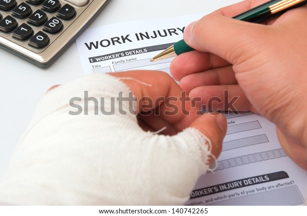 filling-up-a-work-injury-claim-form-with-a-wrapped-hand-calculator-in