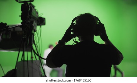 Film crew in green studio shooting video. Chroma - technology of combining two or more images or frames in single composition. Cameraman,director,crew. Filmmaking industry. - Shutterstock ID 1768435160