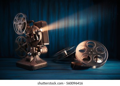 film making scene with old 8mm movie projector with 35mm reels and film on a wooden background with dramatic lighting