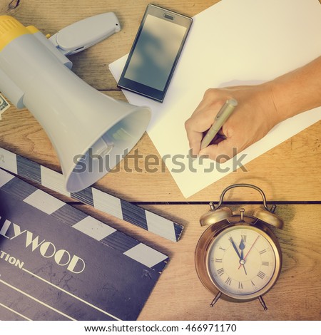 Film production process. Planning to make movie. Clapperboard, megaphone, piggy bank, mobile phone and alarm clock on wooden table background