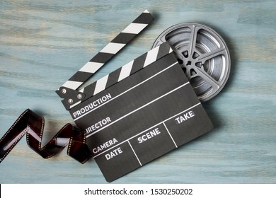 Film stripes with clapperboard and film reel on blue textured background