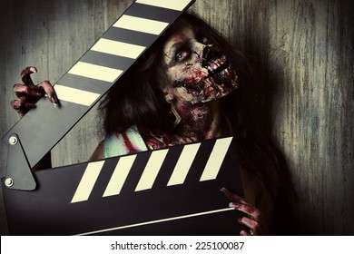 Filming a horror movie. Female zombie holding clapper board. Cinematography. Halloween.