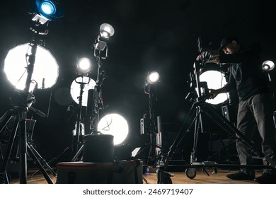 Filmmaker Adjusting Camera Lighting On Set - Powered by Shutterstock