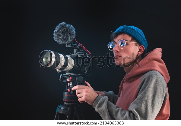 Filmmaker or\
cinematographer using professional camera gear to make\
documentaries and movies. Young cameraman, audiovisual, story\
telling and directing movies\
concepts.