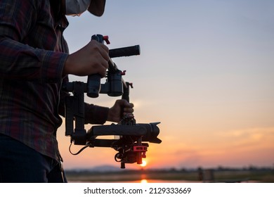 Filmmaker or content creator using stabilizer gimbal camera take video footage on the location outdoor