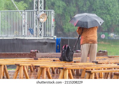 The Filmmaker Is Filming The Event In Rainy Weather Hiding Under An Umbrella.