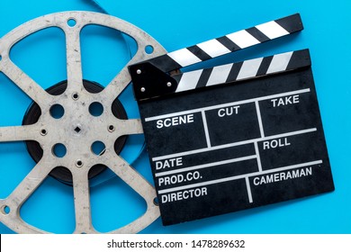 Filmmaker profession with clapperboard and video tape on blue background top view