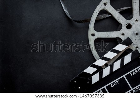 Filmmaker profession with clapperboard and video tape on black background top view copyspace
